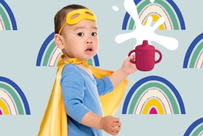 a little boy wearing a cape and holding a cup