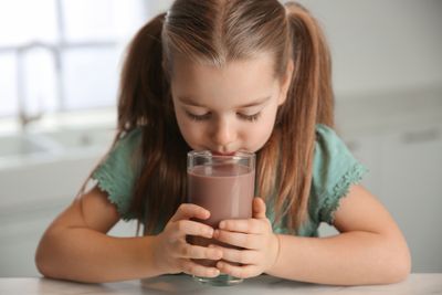 a little girl holding a glass of chocolate milk