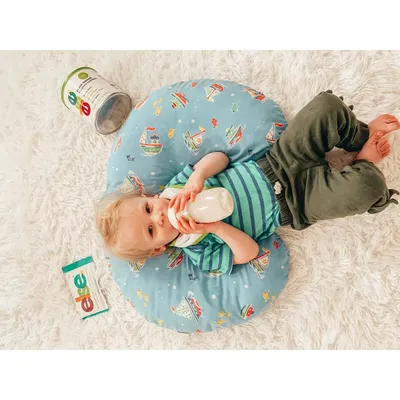 a baby drinking from a bottle while laying on the floor