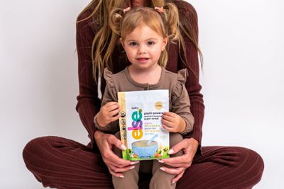 a little girl sitting on a woman's lap reading a book