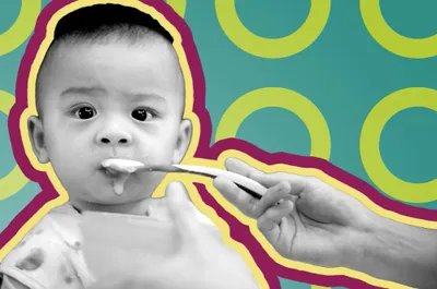 a baby being fed with a spoon by a person