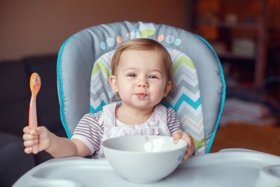 A baby in a high chair eating from a bowl