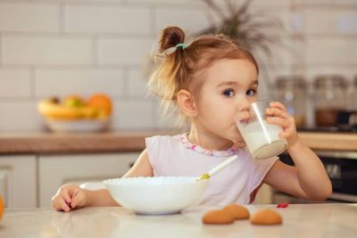 a little girl drinking milk from a glass