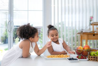 two little girls sitting at a table eating food