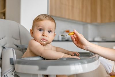 A baby sitting in a high chair eating food