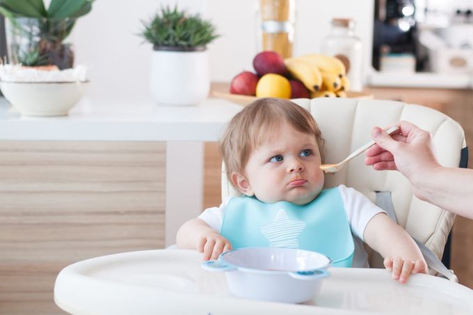 a woman feeding a baby with a spoon