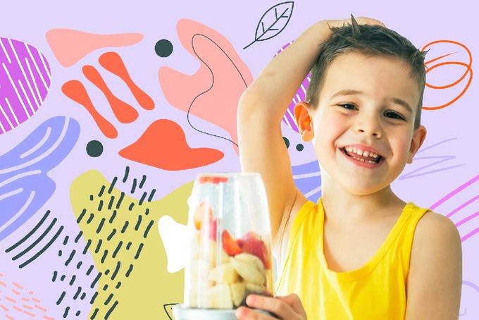 a young boy holding a blender with fruit in it