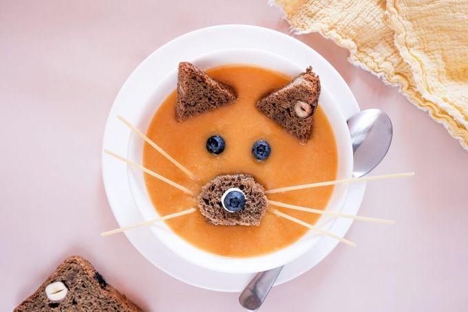 a bowl of soup with a cat face made out of bread