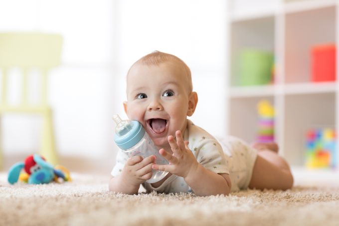 a baby laying on the floor with a bottle