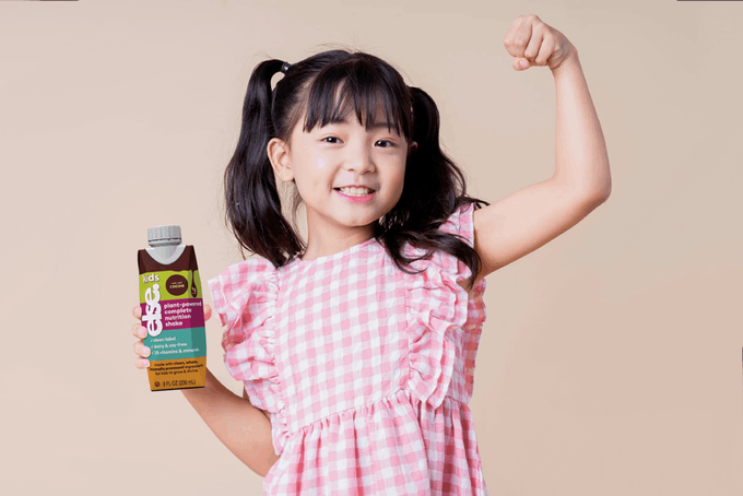 A kid holding Else's protein shake for kids.