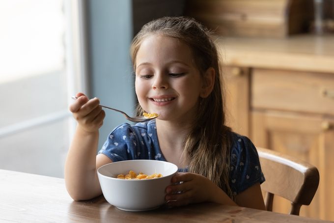 A little picky eater girl eating healthy food at the table.