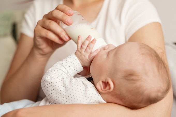 a woman feeding a baby milk from a bottle