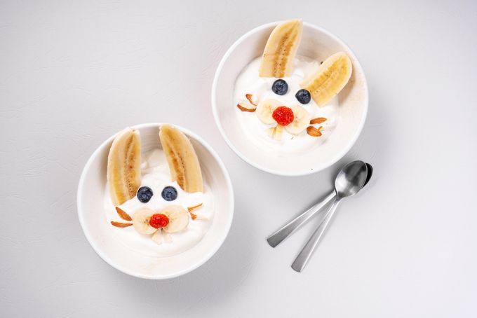 two bowls of yogurt with bananas and blueberries in the shape of a