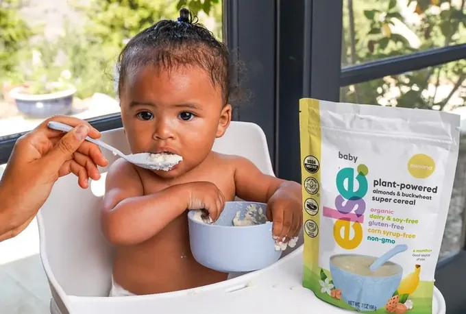 a baby sitting in a high chair eating from a bowl