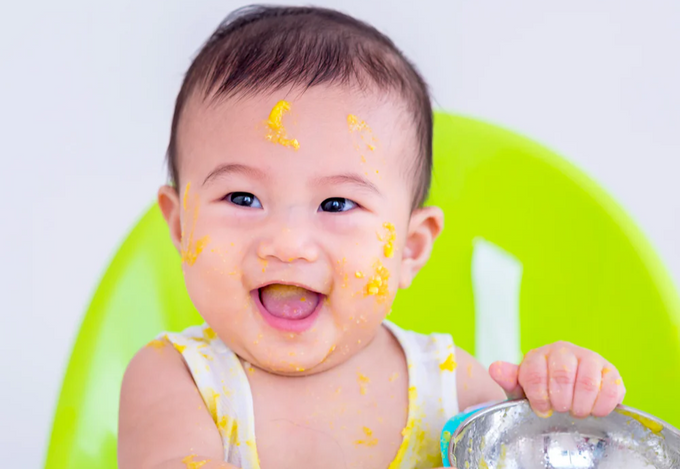 a baby sitting in a highchair with food all over his face