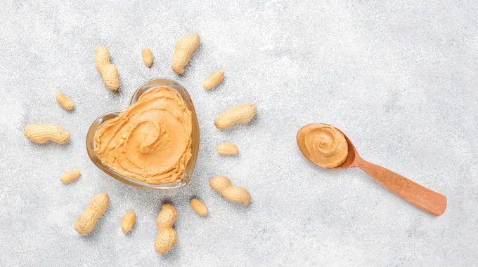 a jar of peanut butter next to a spoon