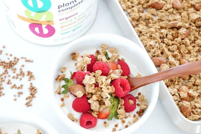 a bowl of granola next to a container of yogurt