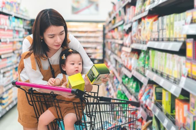 Asian mother and her daughter buying food at a huge supermarket.