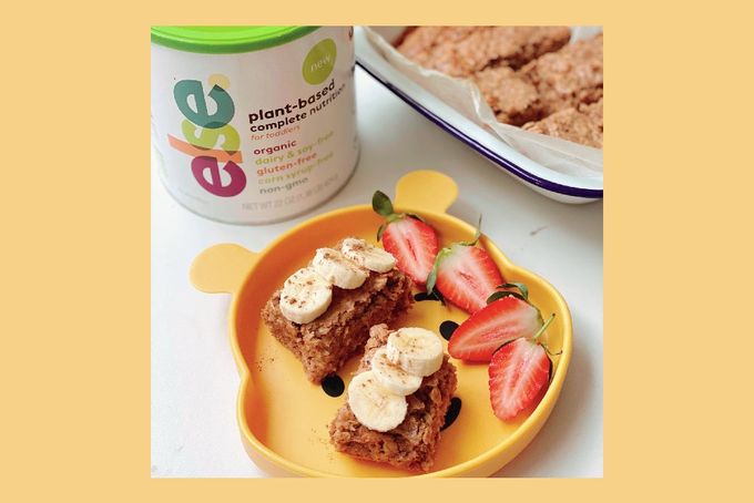 a yellow plate topped with a piece of cake next to a container of yogur