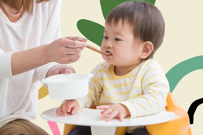 a woman feeding a baby with a spoon