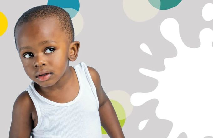 A young boy in a tank top standing in front of a colorful background