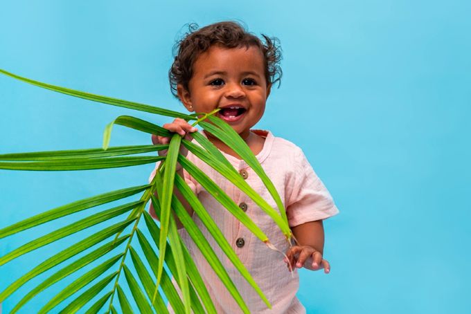 a little girl holding a palm leaf in front of her face