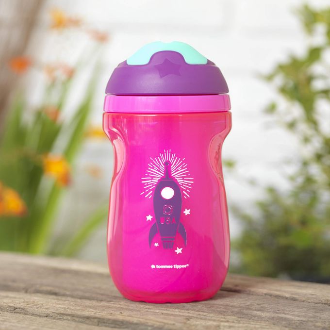 a pink and purple sippy cup sitting on top of a wooden table