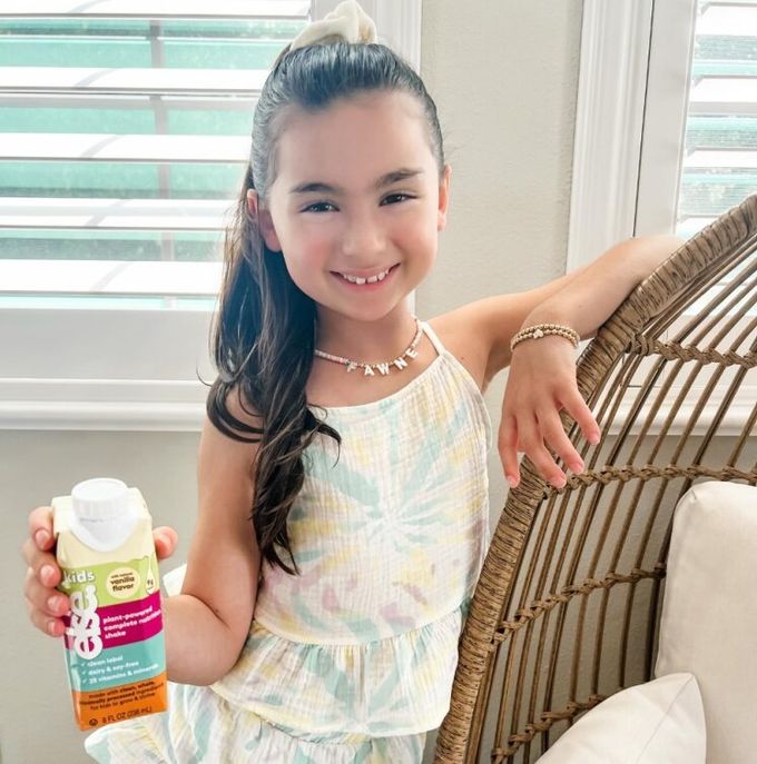 a little girl holding a bottle of sunscreen