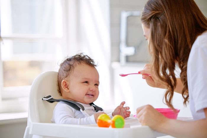 A woman feeding a baby with a spoon.