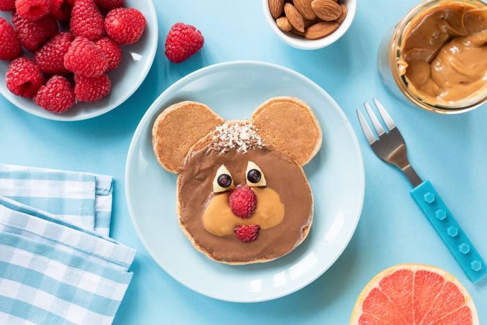 A plate topped with pancakes covered in frosting and a mouse face.