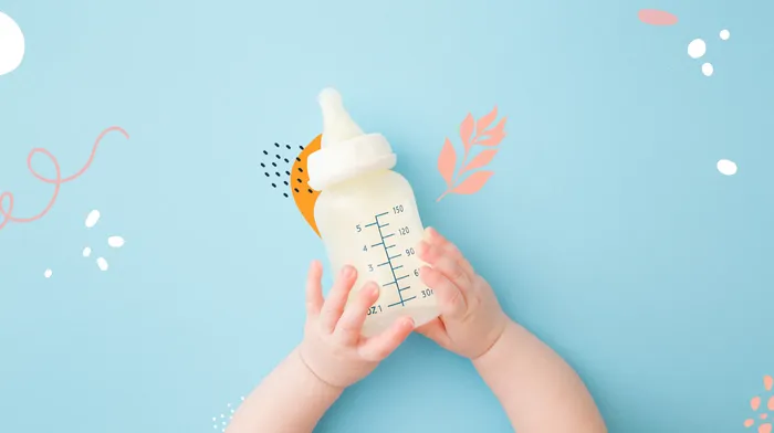 Baby's hands holding a bottle of milk.