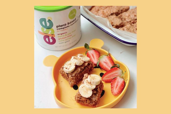 a yellow plate topped with a piece of cake next to a container of yogur