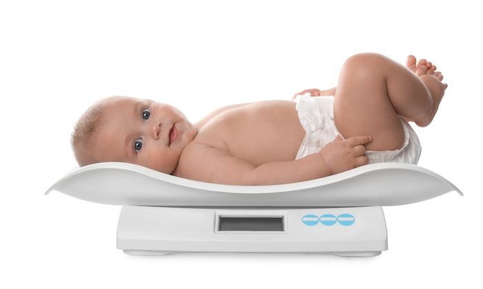 A baby laying on top of a scale.