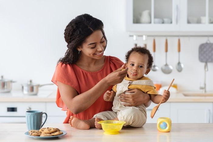 A woman holding a baby in a kitchen.