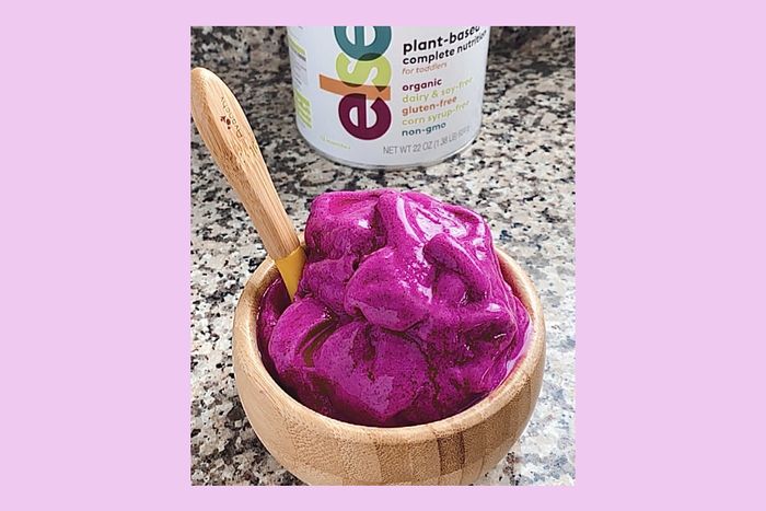 a wooden bowl filled with purple powder next to a jar of yogurt