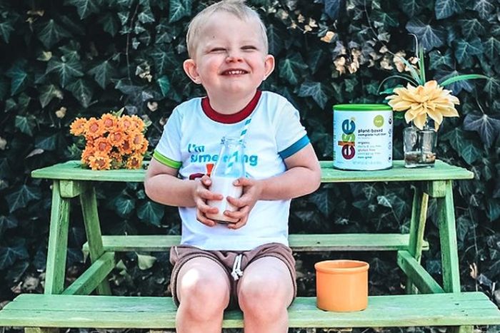 a little boy sitting on a green bench