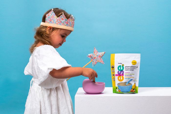 a little girl in a white dress and a pink cup