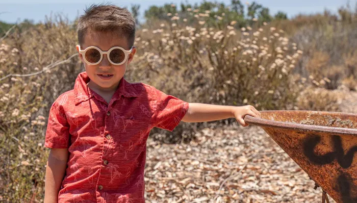 A young boy wearing sunglasses and a red shirt.