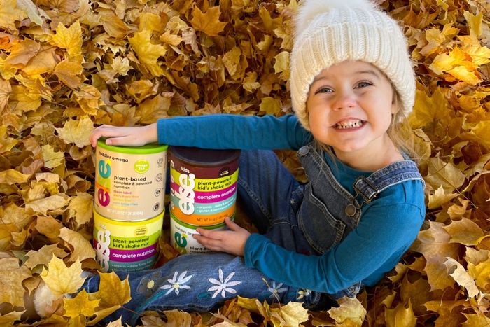 a little girl sitting on a pile of leaves