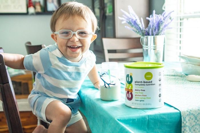 a little boy sitting at a table with a can of oatmeal