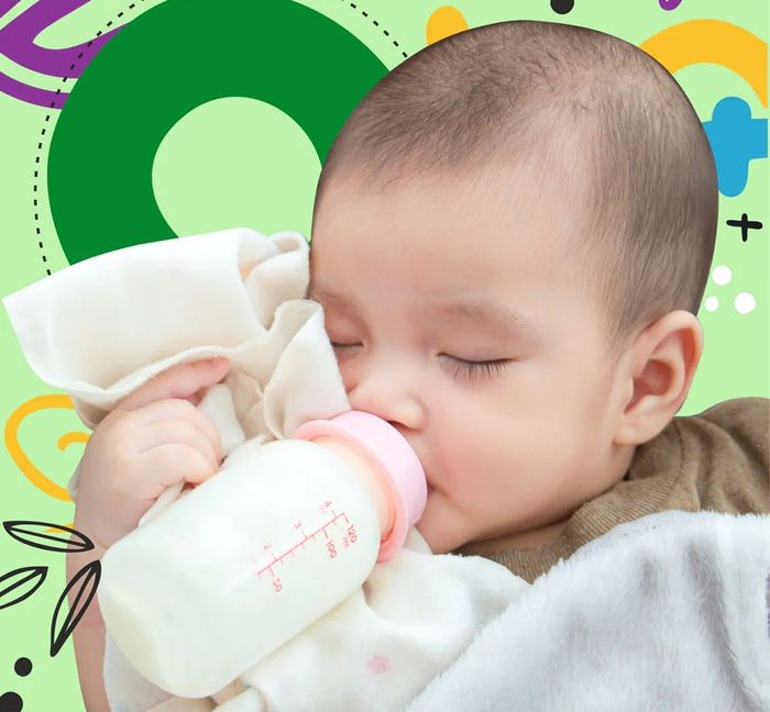 a baby drinking from a bottle while laying on top of a blanket