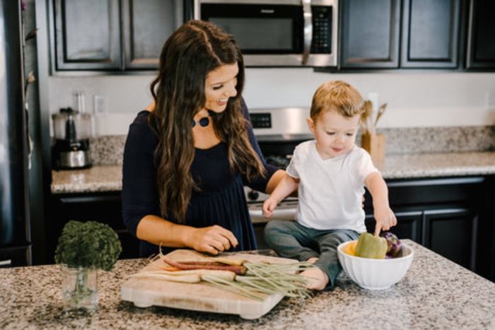 a woman and a child in a kitchen preparing food