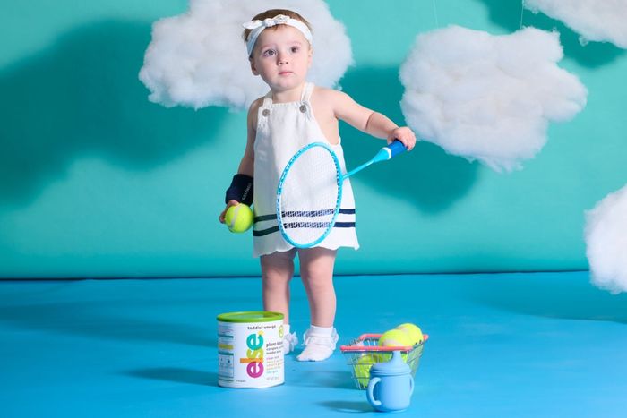 a little girl holding a tennis racket and ball