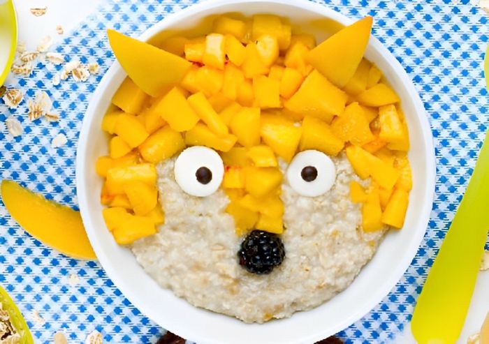 A bowl of oatmeal with a face made out of fruit.