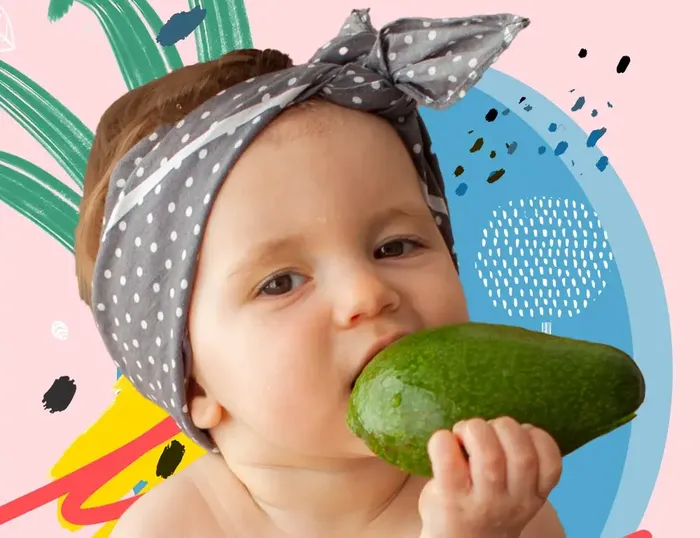 a baby wearing a bandana eating a cucumber