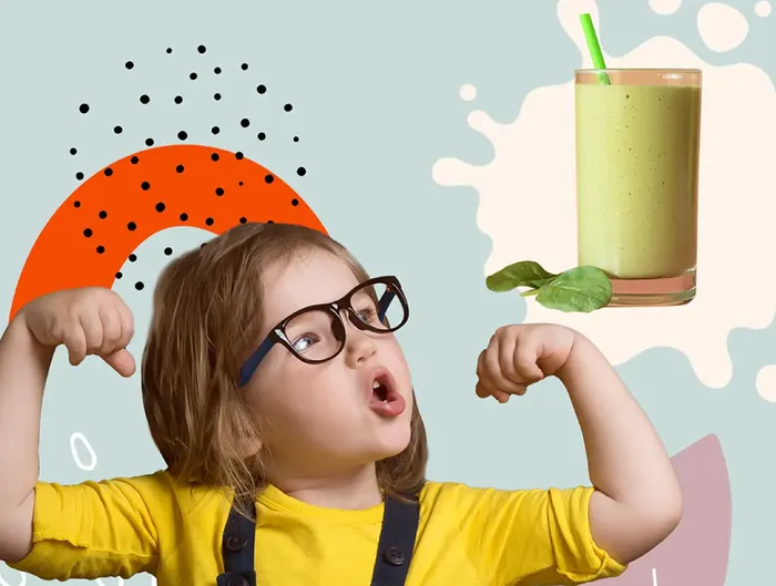 a little girl wearing glasses holding a green smoothie