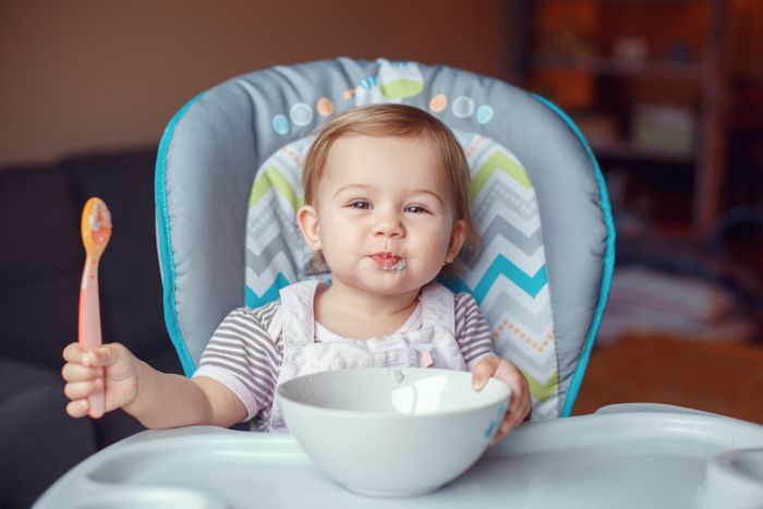 A baby in a high chair eating from a bowl