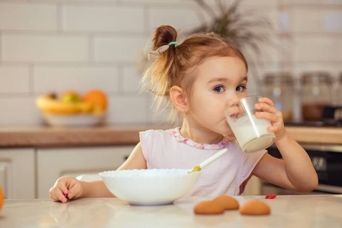 a little girl drinking milk from a glass