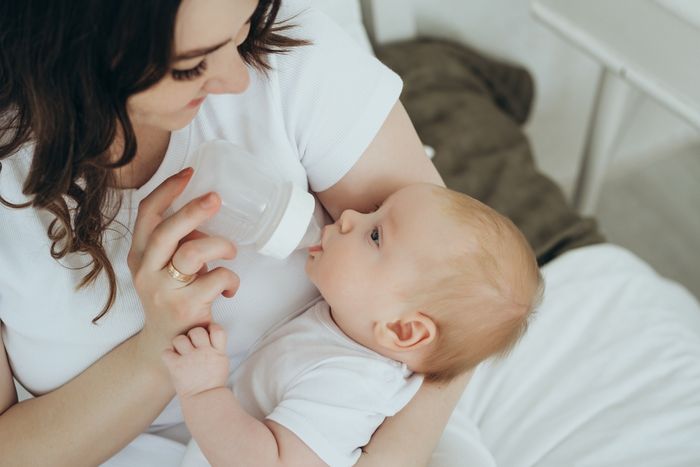 a woman feeding a baby with a bottle