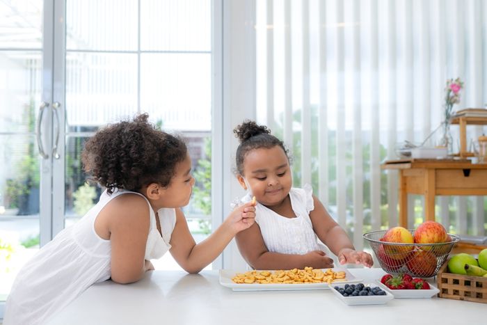 two little girls sitting at a table eating food